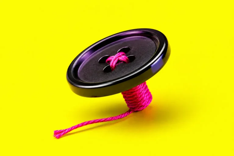 Bouton noir cousu avec fil rose sur fond jaune néon flashy