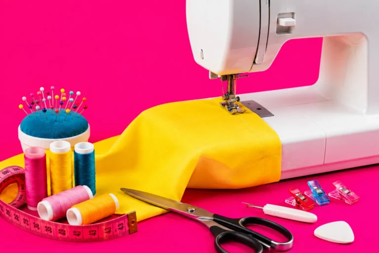 Machine à coudre avec tissu jaune et accessoires couture sur fond rose flashy