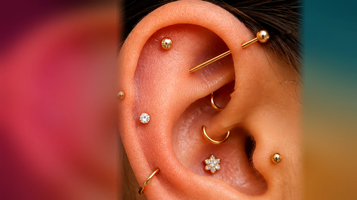Oreille adulte portant plusieurs types de piercings élégants en or